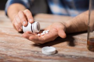 a person dumps pills into their hand possibly struggling with benzo abuse