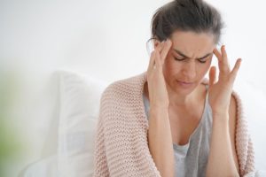 a person holds their head in pain potentially struggling with post acute withdrawal syndrome