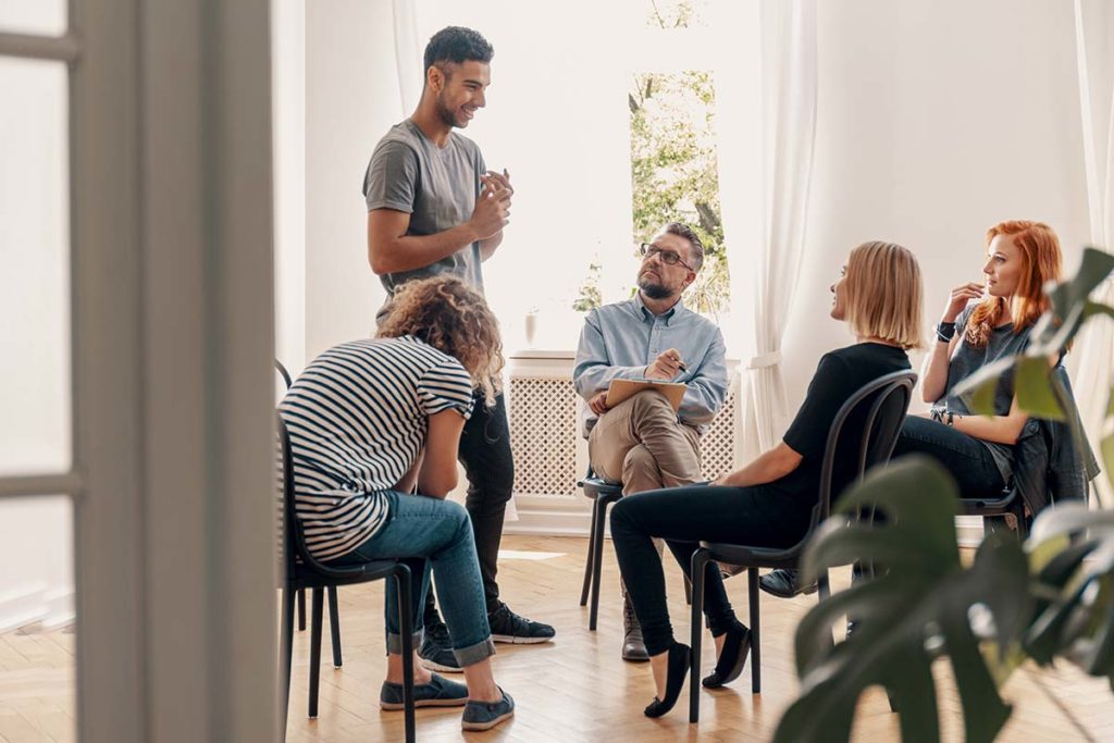 Four people convening and enjoying group therapy benefits